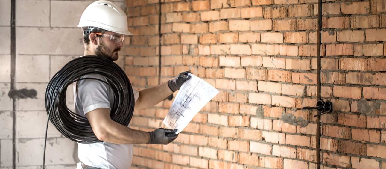 Electrician with construction tools, looking at drawings on the construction site.Repair and handyman concept.