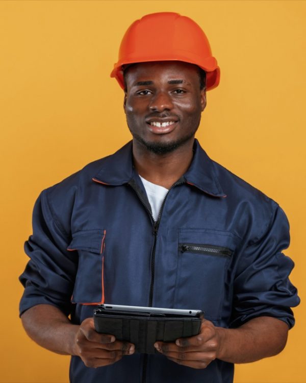 Construction worker in hard hat and with tablet. Handsome black man is in the studio against yellow background